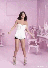 Animated dancing girl in white blouse, black shorts and silver boots spins around in a circle as she dances